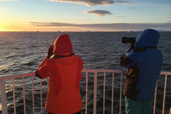 Two travellers photograph an Antarctic sunrise