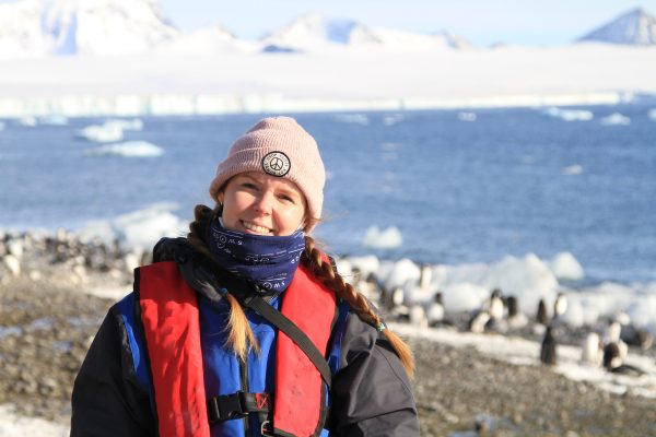 A woman wrapped up warm on an Antarctic beach in the sun